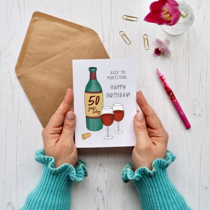 hands holding wine aged to perfection 50th birthday card